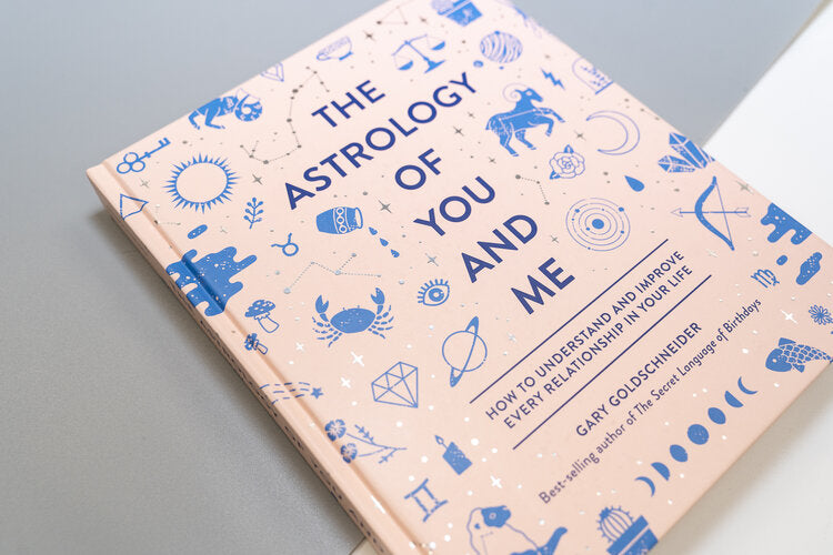 Pink book with blue images of sun, The Astrology of You and Me